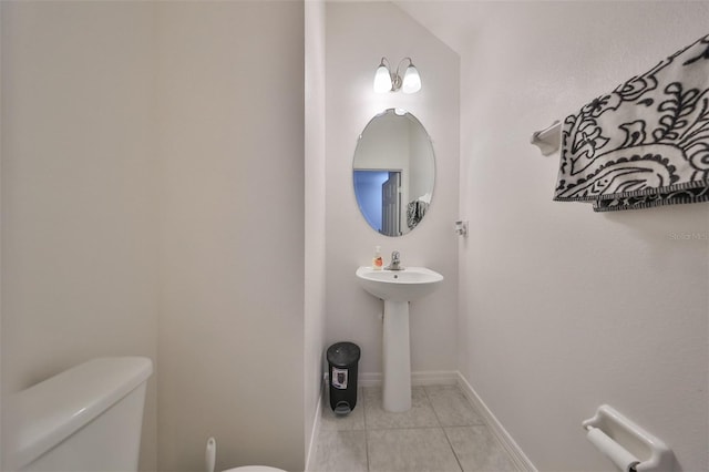 bathroom with toilet, sink, and tile patterned floors