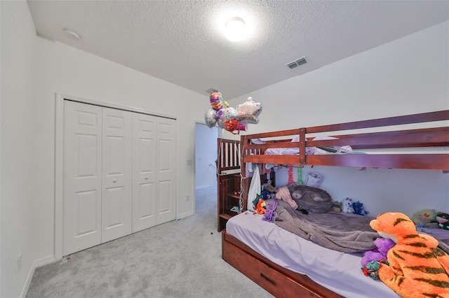 bedroom featuring light carpet, a textured ceiling, and a closet