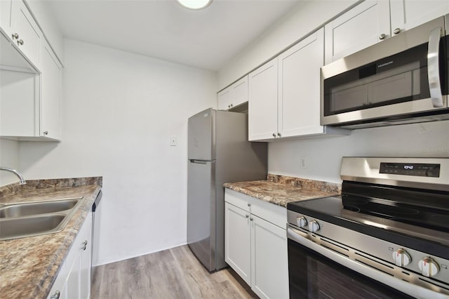 kitchen featuring light wood-type flooring, sink, white cabinets, appliances with stainless steel finishes, and light stone countertops