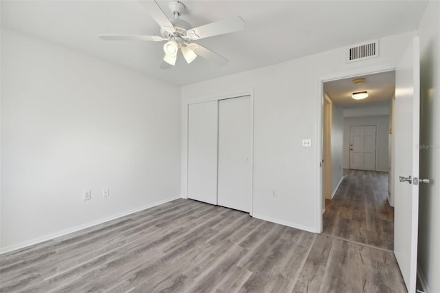 unfurnished bedroom featuring ceiling fan, a closet, and wood-type flooring