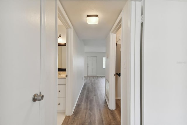 corridor with wood-type flooring, a textured ceiling, and sink