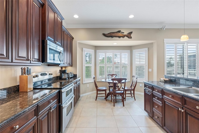 kitchen featuring hanging light fixtures, light tile patterned floors, crown molding, appliances with stainless steel finishes, and dark stone counters