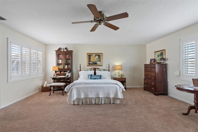 bedroom with ceiling fan, light colored carpet, and a textured ceiling