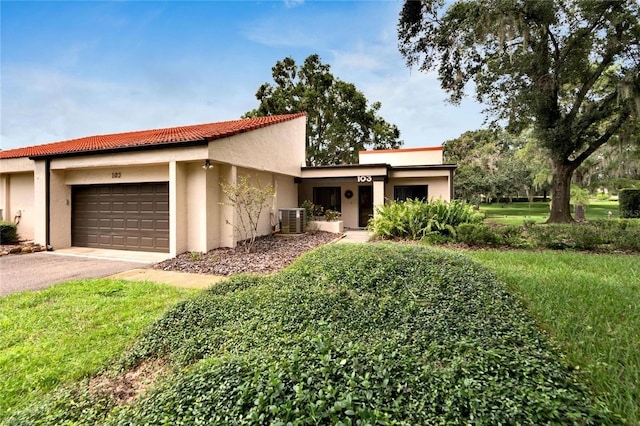 mediterranean / spanish-style house featuring central AC unit, a garage, and a front lawn