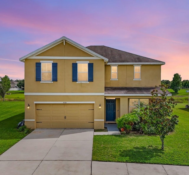 traditional home with a garage, driveway, stucco siding, and a front lawn
