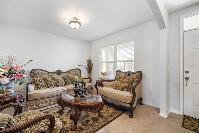 living area featuring light tile patterned floors, arched walkways, and baseboards