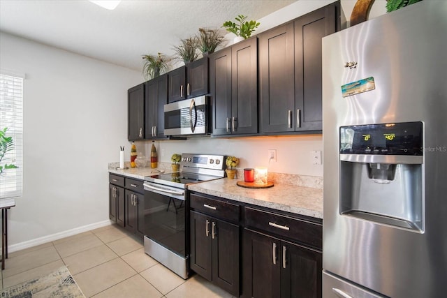 kitchen with light countertops, light tile patterned floors, stainless steel appliances, baseboards, and dark brown cabinets