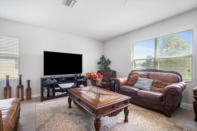 living room featuring a healthy amount of sunlight, visible vents, baseboards, and light tile patterned floors