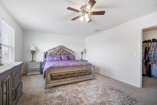 bedroom with a ceiling fan, a walk in closet, baseboards, visible vents, and carpet