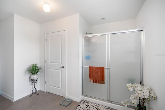 bathroom with a shower stall, baseboards, and tile patterned flooring