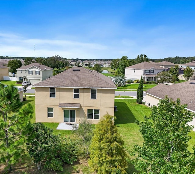 back of house with stucco siding, a lawn, a residential view, a shingled roof, and a patio area
