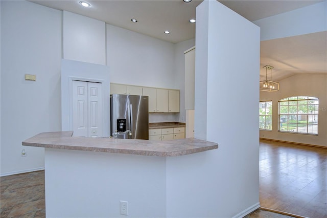 kitchen with stainless steel refrigerator with ice dispenser, vaulted ceiling, decorative light fixtures, and kitchen peninsula