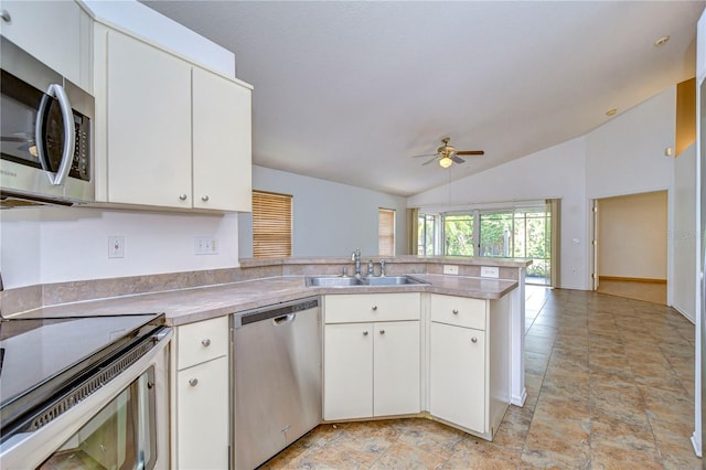 kitchen featuring lofted ceiling, sink, white cabinetry, stainless steel appliances, and kitchen peninsula