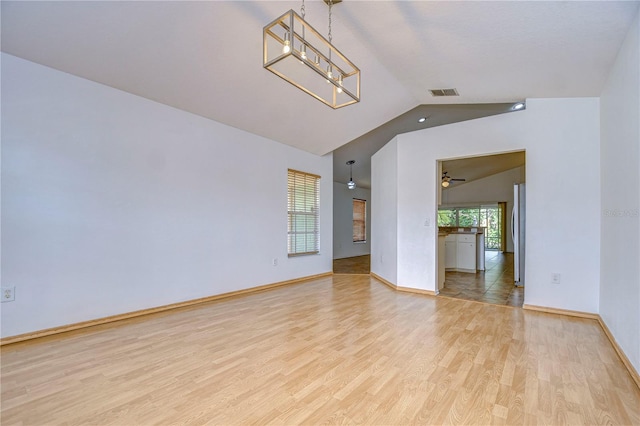 spare room featuring lofted ceiling, a notable chandelier, and light wood-type flooring