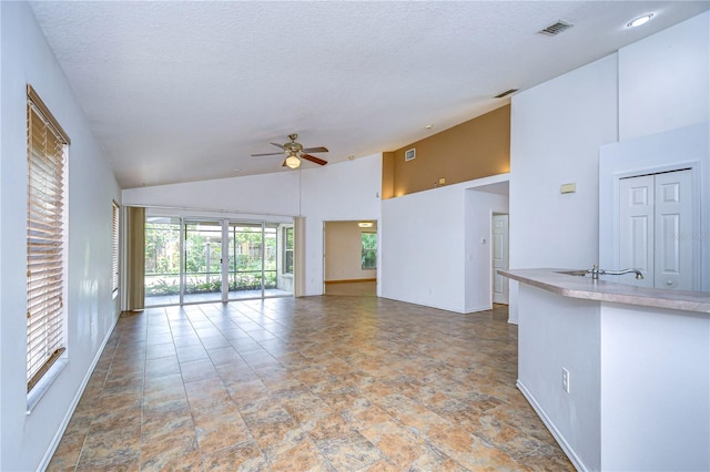 unfurnished living room with a textured ceiling, high vaulted ceiling, and ceiling fan