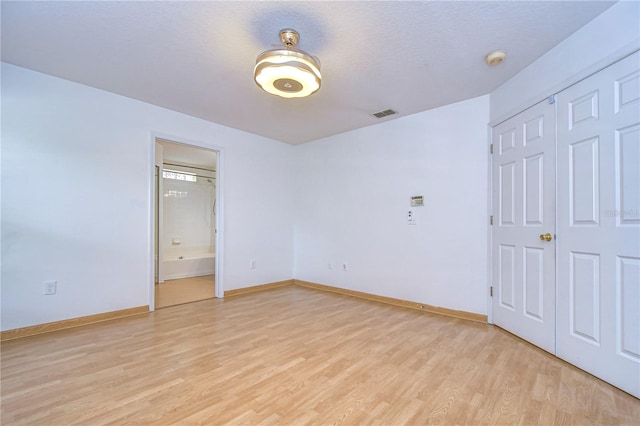 unfurnished bedroom with light hardwood / wood-style floors, a closet, and a textured ceiling