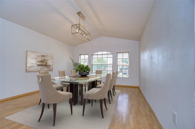 dining room with vaulted ceiling, an inviting chandelier, and light hardwood / wood-style floors