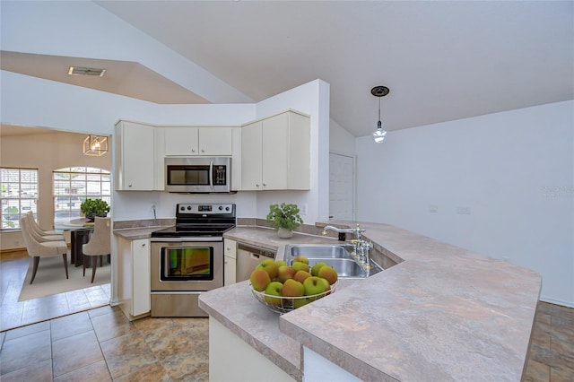 kitchen with sink, hanging light fixtures, stainless steel appliances, white cabinets, and vaulted ceiling