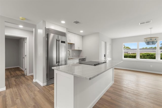 kitchen with light hardwood / wood-style floors, sink, white cabinetry, built in fridge, and light stone countertops