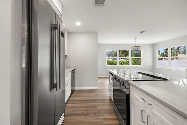 kitchen with appliances with stainless steel finishes, light stone countertops, dark hardwood / wood-style floors, and white cabinets