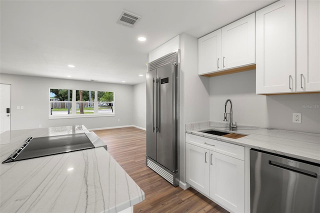 kitchen with light stone countertops, stainless steel appliances, white cabinets, and sink