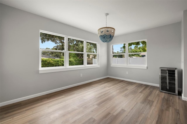 unfurnished room featuring hardwood / wood-style floors, heating unit, plenty of natural light, and a chandelier