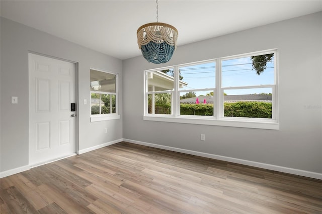 unfurnished dining area featuring a notable chandelier and light wood-type flooring