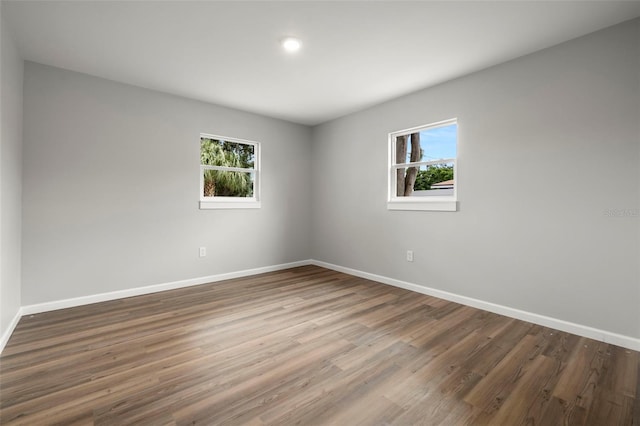 empty room with plenty of natural light and dark hardwood / wood-style flooring