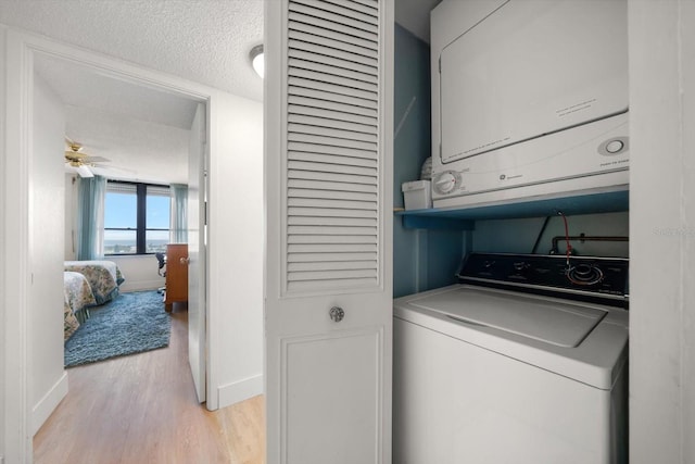 washroom featuring stacked washer / dryer, ceiling fan, light hardwood / wood-style floors, and a textured ceiling