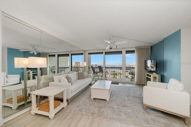 living room with hardwood / wood-style flooring, ceiling fan, a textured ceiling, and a wall of windows