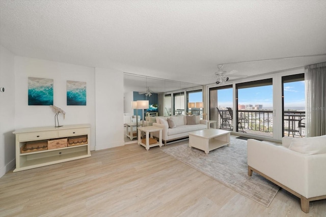 living room featuring a wall of windows, a textured ceiling, hardwood / wood-style flooring, and ceiling fan