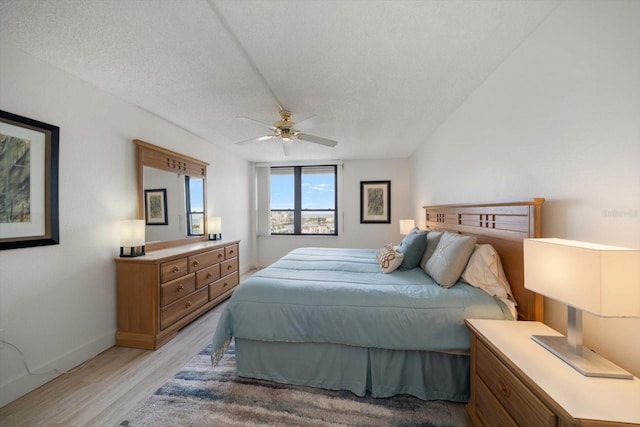 bedroom featuring ceiling fan, light hardwood / wood-style flooring, and a textured ceiling