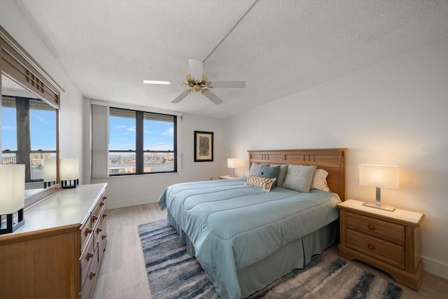 bedroom with ceiling fan, a textured ceiling, and hardwood / wood-style flooring