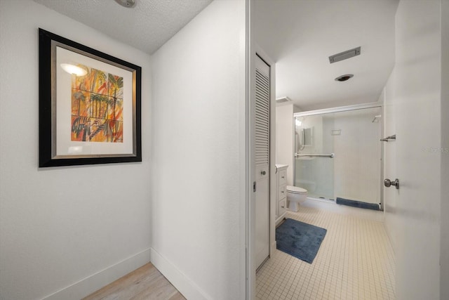 corridor with light hardwood / wood-style floors and a textured ceiling