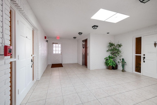 tiled spare room with a textured ceiling and brick wall