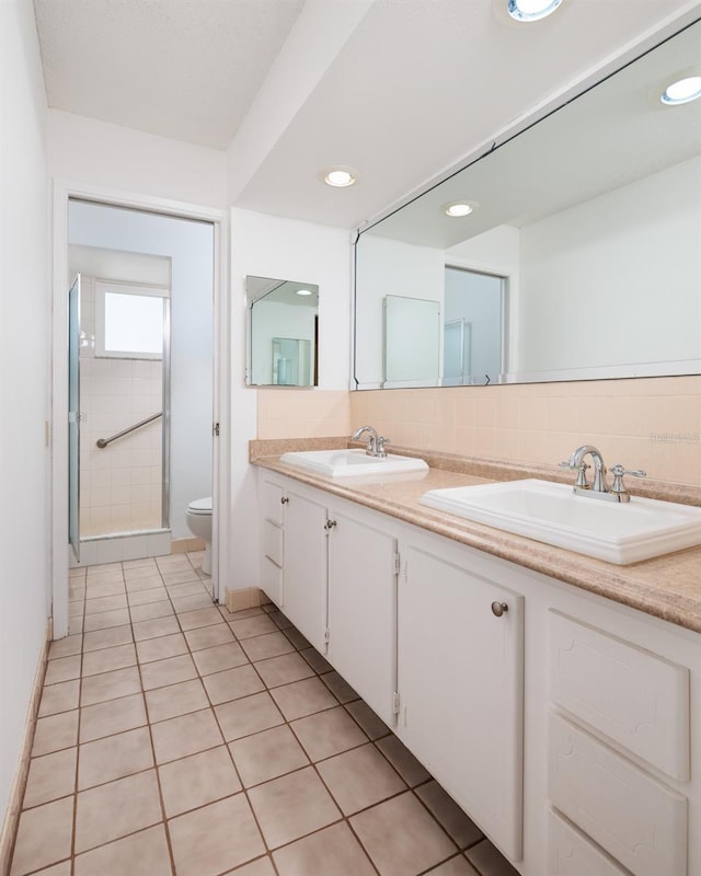 bathroom featuring vanity, toilet, tile patterned flooring, and a shower with door