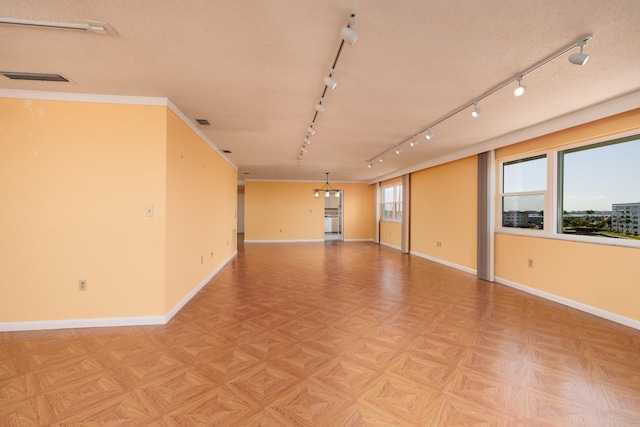 empty room with light parquet floors, rail lighting, ornamental molding, and a textured ceiling