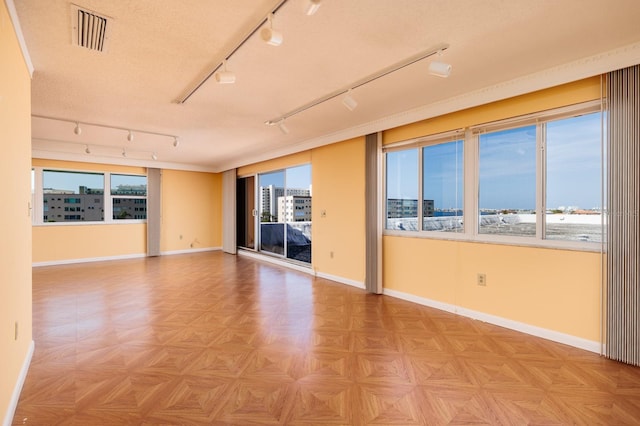 unfurnished room featuring light parquet floors, a textured ceiling, and rail lighting