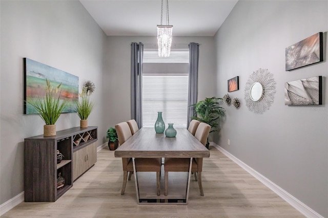 dining room with light hardwood / wood-style floors and a chandelier