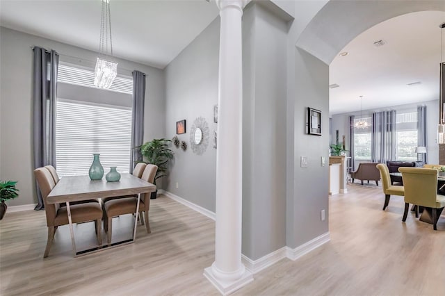 dining area with an inviting chandelier, ornate columns, and light wood-type flooring