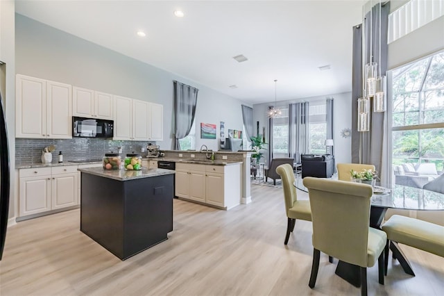 kitchen with a healthy amount of sunlight, black appliances, a center island, and hanging light fixtures