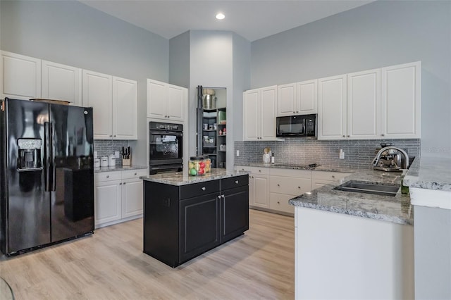 kitchen with light hardwood / wood-style flooring, backsplash, sink, black appliances, and white cabinets