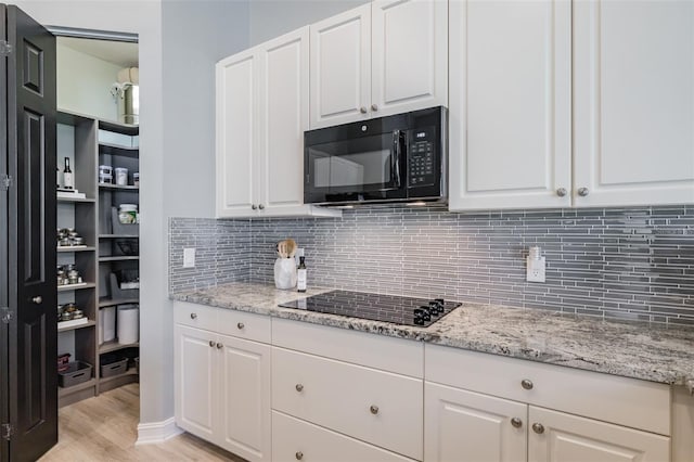 kitchen featuring black appliances, white cabinets, decorative backsplash, and light hardwood / wood-style floors