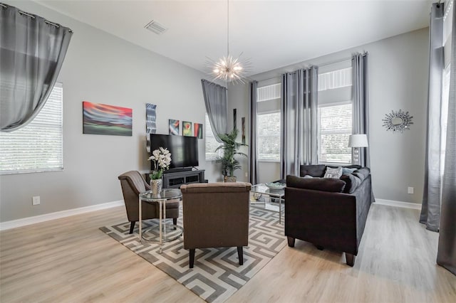 living room with light hardwood / wood-style flooring, a chandelier, and plenty of natural light