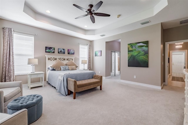 carpeted bedroom featuring connected bathroom, ceiling fan, and a raised ceiling