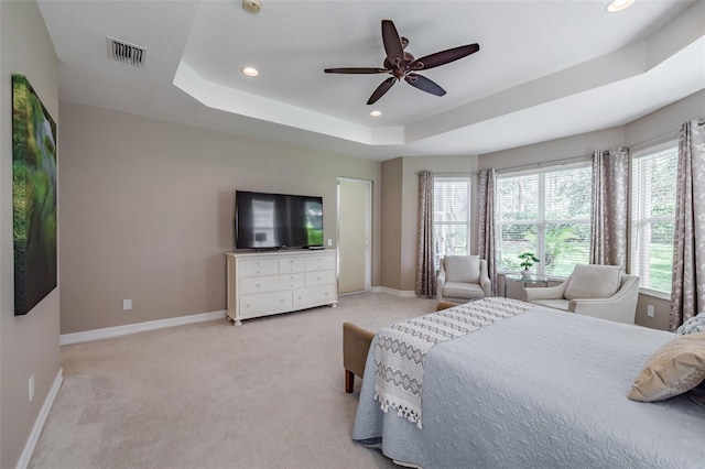 bedroom featuring light carpet, a tray ceiling, and ceiling fan