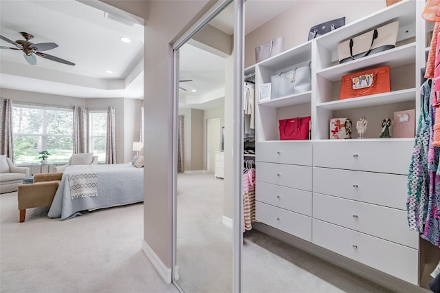 carpeted bedroom with a raised ceiling and ceiling fan