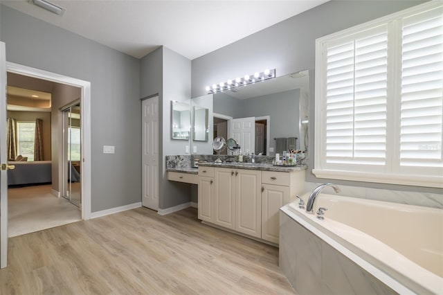 bathroom featuring vanity, wood-type flooring, a healthy amount of sunlight, and a bathing tub