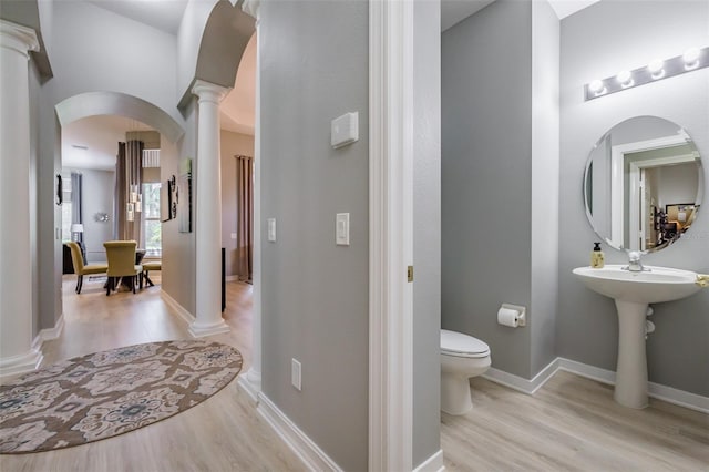 bathroom with decorative columns, wood-type flooring, and toilet