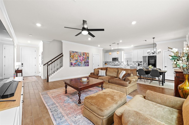 living room featuring light hardwood / wood-style floors, ceiling fan with notable chandelier, and ornamental molding